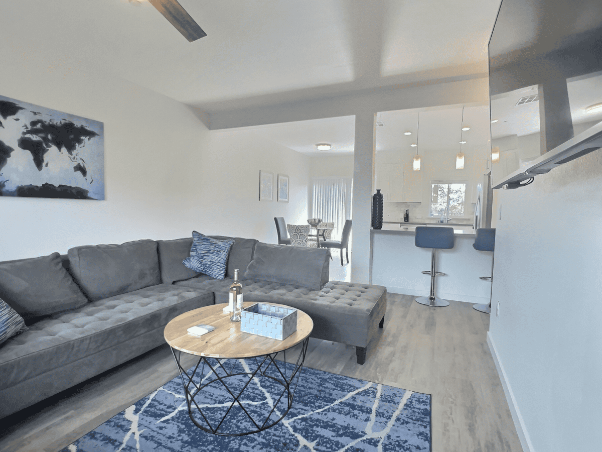 Living room with L-shaped couch, smart TV, and open kitchen.