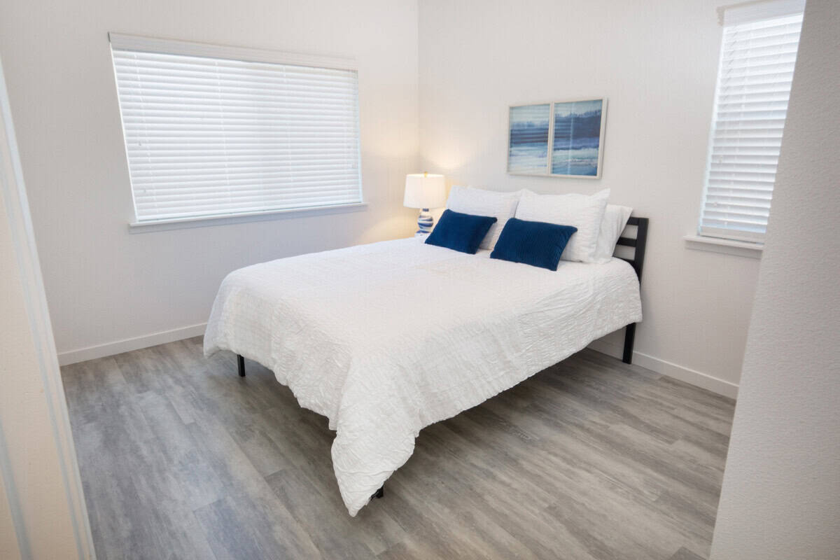 Bedroom 2 with queen bed, nightstands, and views of olive orchard.